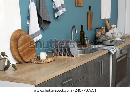 Wooden kitchen counters with cutting boards, plate rack, sink, electric stove and utensils Royalty-Free Stock Photo #2407787631