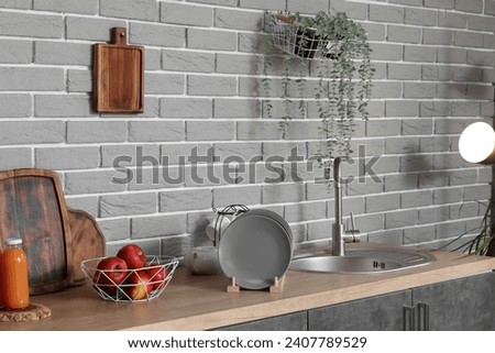 Wooden countertop with sink, apples and plate rack in modern kitchen Royalty-Free Stock Photo #2407789529