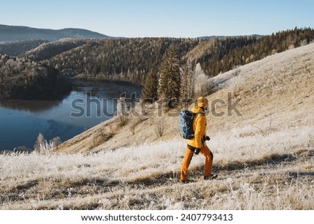 Mountain trekking in winter in the mountains, a guy travels with a backpack on hilly terrain, cold morning in the forest, hiking. High quality photo