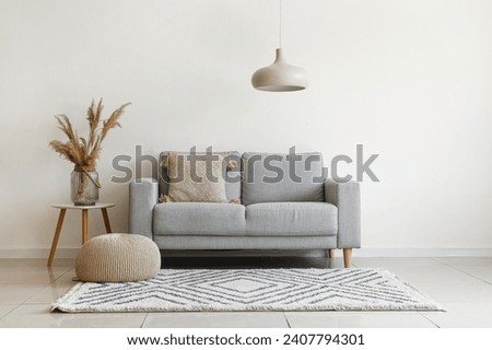 Grey sofa with cushion and pampas grass on coffee table in light living room Royalty-Free Stock Photo #2407794301