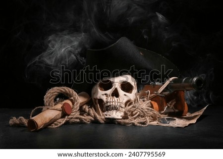 Human skull with toy model of cannon, pirate hat, world map and scroll on black background