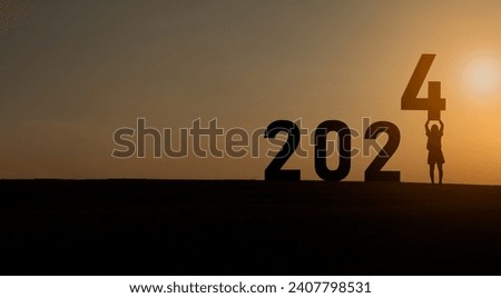 Woman holding standing happy new year 2024 concept, silhouette of woman stand lawn and success with beautiful sunset background. Happy New Year 2023 use for web banner and advertisement.