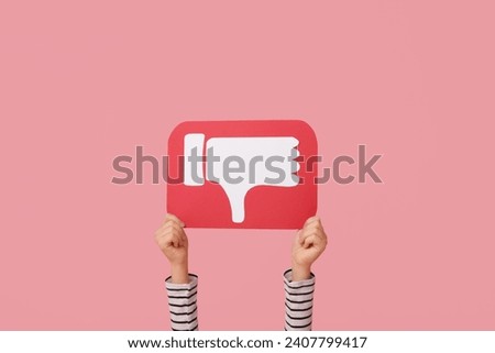 Little girl with dislike icon on pink background
