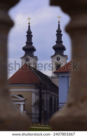 Urban image of Timisoara, Romania. The towers of the Serbian Church can be seen between the opening in the wall. Royalty-Free Stock Photo #2407801867
