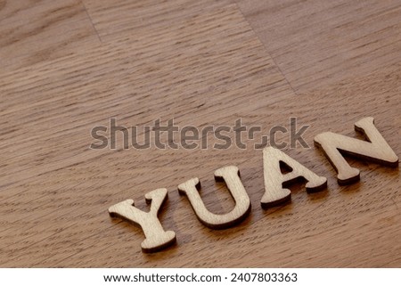 Chinese yuan concept, yuan word concept made of wooden letters on wooden background with yuan banknote