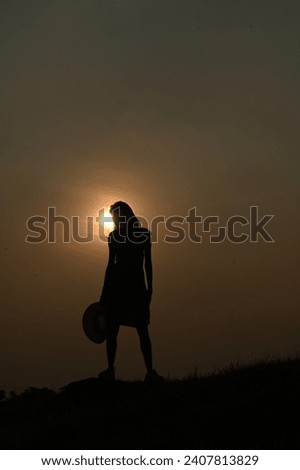 silhouette portrait photo of a girl with hat during sunset. stock image