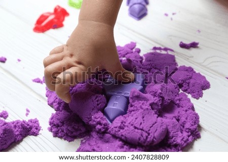 Little child playing with kinetic sand at white wooden table, closeup Royalty-Free Stock Photo #2407828809