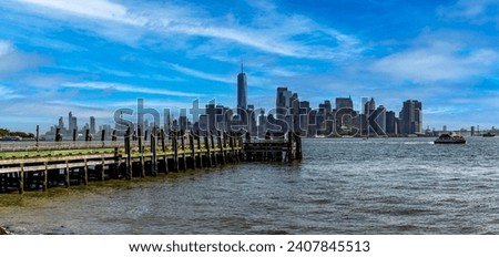 Beautiful panoramic photograph of a pier with the New York skyline in the background, specifically the skyscrapers in Manhattan.
