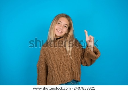 Beautiful kid girl wearing brown knitted sweater  pointing up with fingers number ten in Chinese sign language Shi