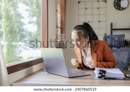 Excited and happy businesswoman, female secretary celebrating success, rejoicing with good news in business, raising hands, good news email. Royalty-Free Stock Photo #2407860519