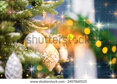 Part of a Christmas tree with decorations in lights and golden bokeh.