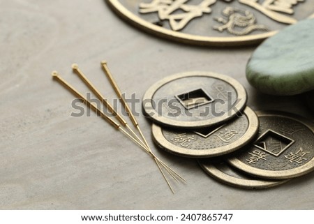 Acupuncture needles and ancient coins on beige marble table, closeup