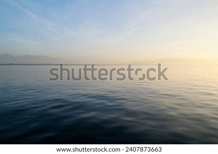 the tranquil transparent waters of lake Constance (Bodensee) with the Swiss Alps in the background on a calm October day on Lindau island, Germany                                Royalty-Free Stock Photo #2407873663