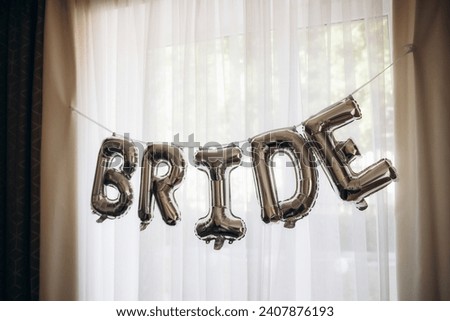 A vertical shot of white balloons with helium and silver balloons with "BRIDE" letters on the wall. High quality photo