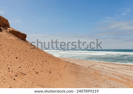 Sand dune next to the ocean at Skeleton Coast in Namibia with blue skies