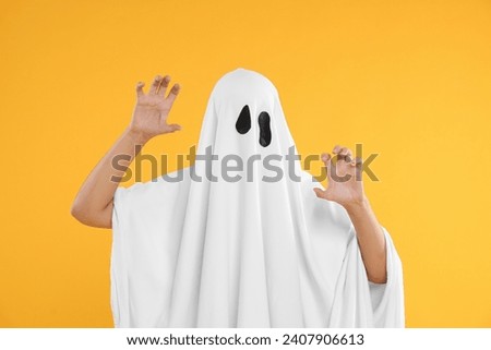 Woman in white ghost costume on yellow background. Halloween celebration