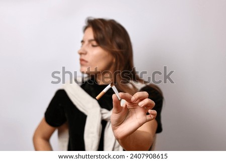 The girl breaks a cigarette in half. The concept of the bad habit of smoking.