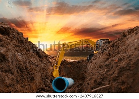 Crawler excavator is digging in the construction site pipeline work on sunset sky background Royalty-Free Stock Photo #2407916327