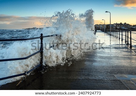 Large Wave breaks onto Amble Pier. Amble Harbour is actually called Warkworth Harbour and is set on the banks of the River Coquet in Northumberland in the North East of England Royalty-Free Stock Photo #2407924773