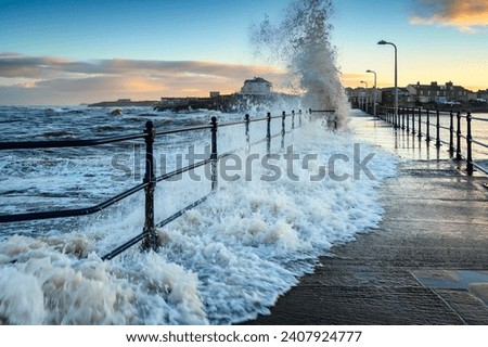 Wave engulfs Amble Pier. Amble Harbour is actually called Warkworth Harbour and is set on the banks of the River Coquet in Northumberland in the North East of England Royalty-Free Stock Photo #2407924777