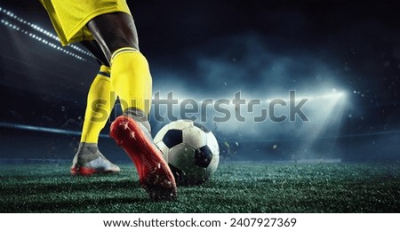 Cropped image of African man's legs, football player in yellow uniform on 3d arena playing, hitting ball. Evening outdoor match. Concept of sport, game, competition, championship. 3D render Royalty-Free Stock Photo #2407927369