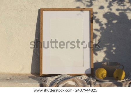 Neutral vertical wooden frame picture mockup against white old textured white wall in sunlight. Fresh yellow lemons fruit, cup of coffee. Mediterranean summer background with light. Floral shadows.