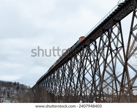 Selective focus low angle view of freight train on 1908 railway trestle bridge seen from during a cloudy winter morning, Cap-Rouge area, Quebec City, Quebec, Canada Royalty-Free Stock Photo #2407948403