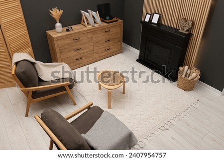 Stylish room with beautiful rug near fireplace. Interior design