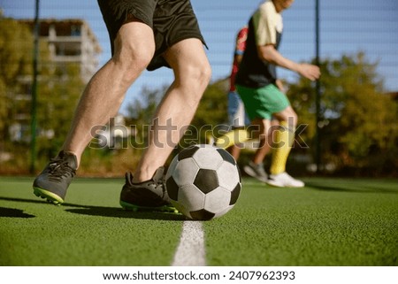 Soccer player kicking ball cropped shot, amateur football match Royalty-Free Stock Photo #2407962393