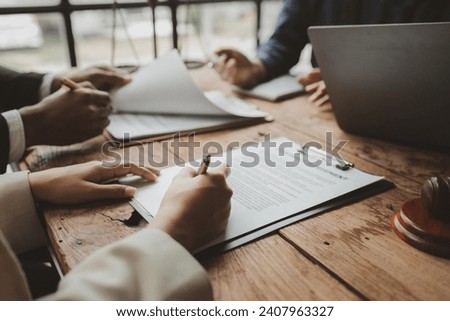Business people negotiating a contract, discussing contract while working together in sunny modern office, unknown businessman and woman with colleagues or lawyers at meeting.
