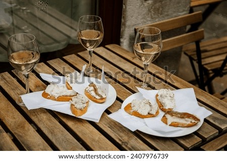 Venice, Italy, 12 February 2023:  Cichetti Venetian tapas with cod mash, cafe restaurant Bacari, Traditional Appetizers snacks accompanied with three glass of white wine, bar food, wooden table Royalty-Free Stock Photo #2407976739
