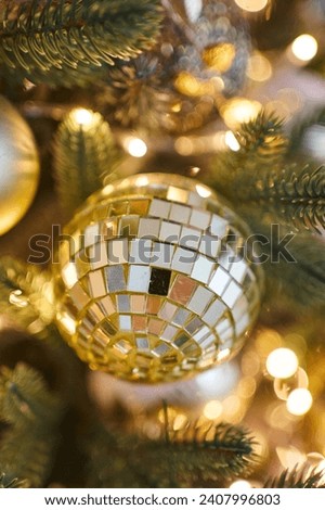 close-up of a New Year's toy disco ball. beautiful New Year tree with golden lights. toys on the Christmas tree close-up. balls and feather. beautiful New Year card