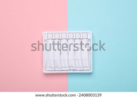 Set of white empty tubes of acrylic or oil paint for creativity on pink blue background. Template for design, mockup