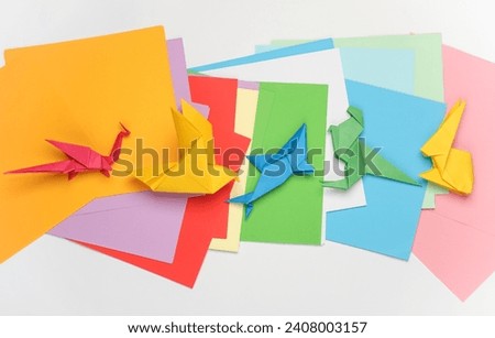 Paper folded origami animal figurines on a white background with colored sheet of papers. Hobbies, creativity