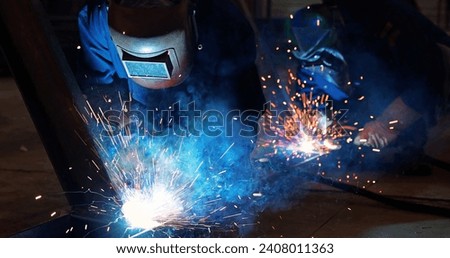 Welders at work in metal industry, welding metal construction. Close-up shot lots of sparks in the factory Royalty-Free Stock Photo #2408011363