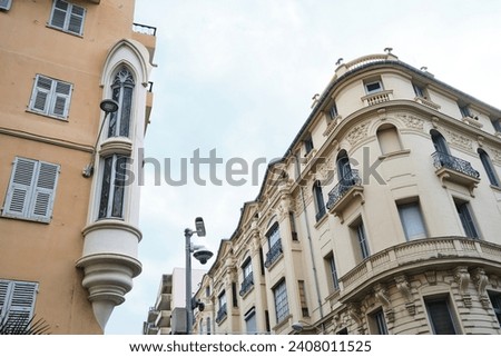 A house with a bay window and a second beautiful house with a rounded corner and false balconies