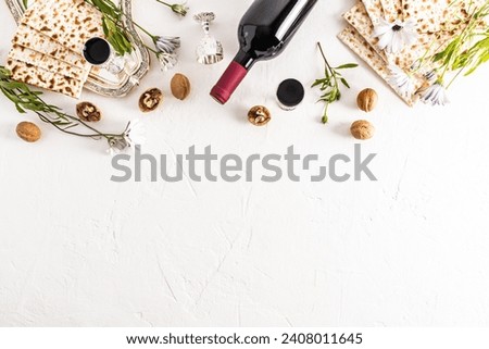 Festive background for the Jewish holiday Passover. Traditional treats, bottle of wine, matza on white background. Top view. A copy space. border Royalty-Free Stock Photo #2408011645