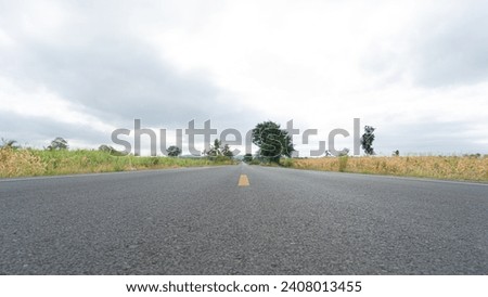 Newly built road with 2 lanes going in opposite directions in the countryside. There is a lane for bicycles. For safety in using the road On both sides of the road are farmers' corn fields.  Royalty-Free Stock Photo #2408013455