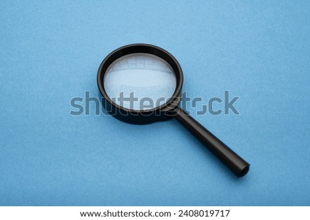 a magnifying glass on blue paper, essence of a searching engine concept quest for information and insights through a visual metaphor. 