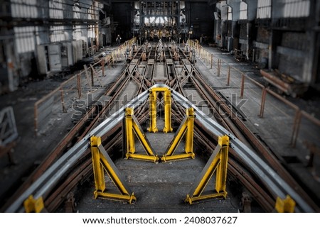 The picture shows an abandoned industrial hall with several tracks leading into it.