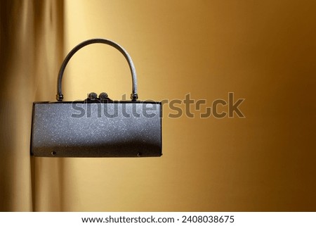 Shiny sparkling silver like woman purse with handle on a yellow background. Creative studio shoot  Royalty-Free Stock Photo #2408038675