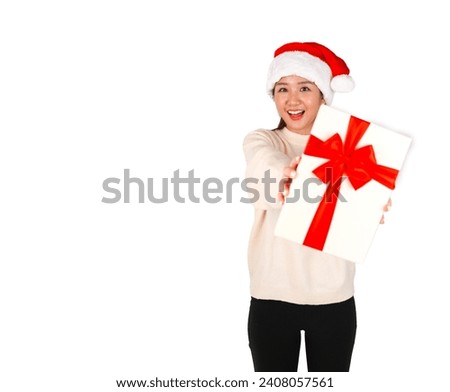 Excited young asian woman holding a gift while wearing a Christmas hat against a white background