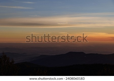 close up view of the central plain area of Friuli Venezia Giulia, during a partially cloudy and foggy autumn evening, with the sunset coloring of orange shades the blue sky Royalty-Free Stock Photo #2408060183