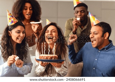 Diverse friends united in birthday celebration, lady celebrating with fellow students making a wish and enjoying bday party together at her home, sharing laughter and warmth of their friendship