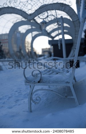 White bench frozen in ice and snow in the park. Harsh climate for walks in the park, vertical photo of cold park for lovers