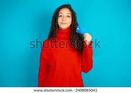 Photo of happy cheerful smiling positive Beautiful girl with curly hair wearing red knitted sweater recommend credit card
