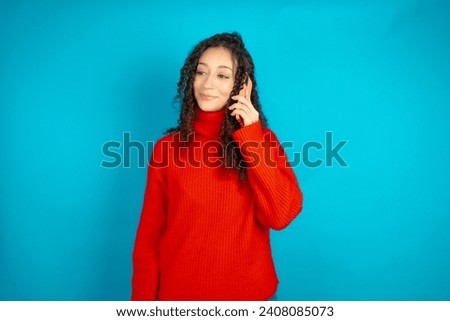 Happy joyful charming Beautiful girl with curly hair wearing red knitted sweater talk speak phone smile good mood