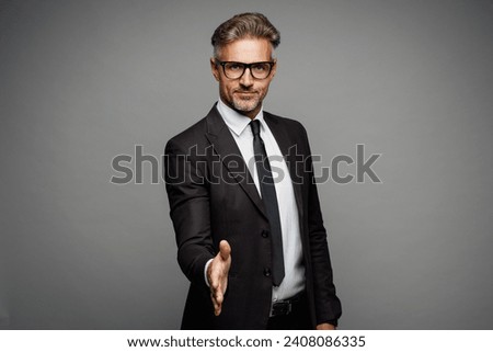 Adult successful employee business man corporate lawyer wear classic formal black suit shirt tie work in office stretch hands for handshake gesture isolated on plain grey background studio portrait Royalty-Free Stock Photo #2408086335