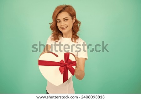 positive girl hold heart gift box on blue background