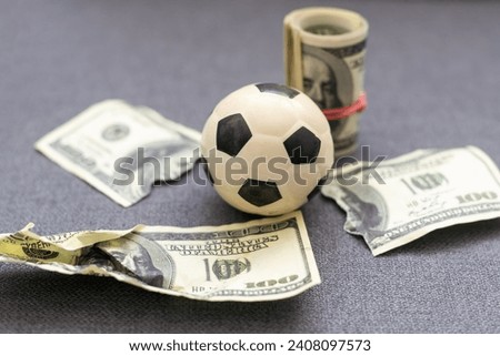 Small soccer ball on heap of dollars isolated on a white background